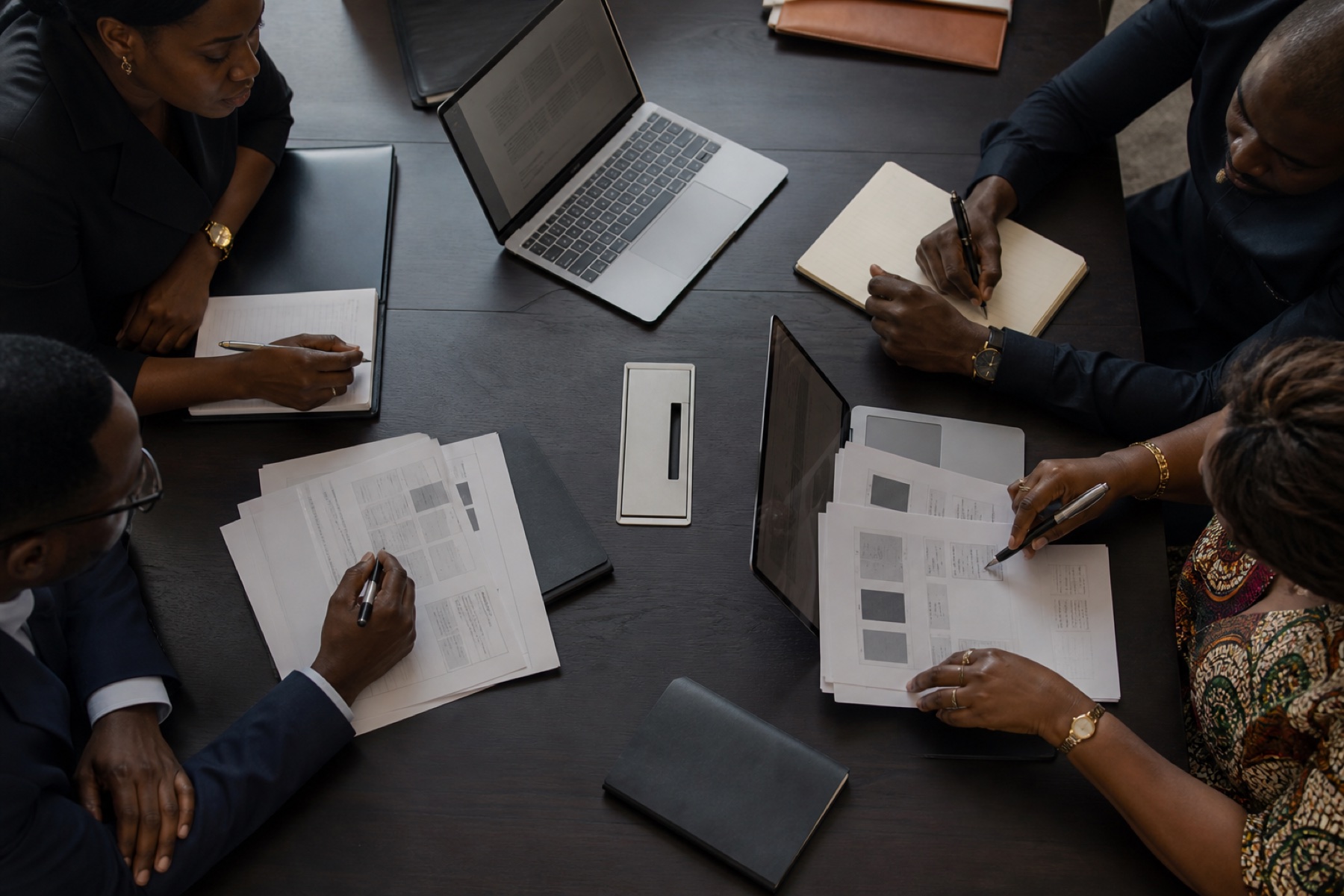 African executives reviewing documents and digital workflows around a working table